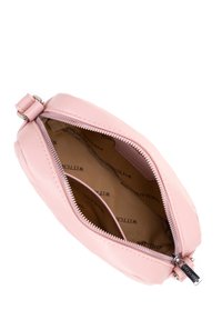 Sacco in pelle rosa chiaro con cerniera aperta, fodera interna beige stampata con la scritta "WITTCHEN" e una piccola tasca interna.