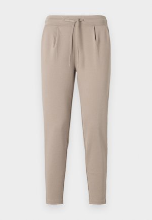 Beige jogger pants made of soft fabric, featuring an elastic waistband with drawstring, and side pockets. Tapered leg design.