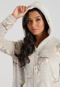 Fleece hætteonesie i cremefarvet med blød tekstur og dyreprint. Har en frontlynlås og lommer.