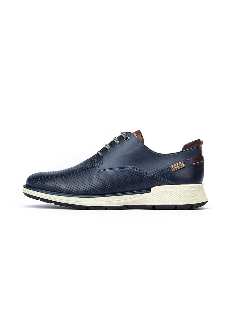 Chaussures en cuir bleu marine avec texture perforée, semelle en caoutchouc beige et accents marron. Présentent six œillets et un design à bout arrondi.