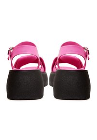 Sandales roses avec une finition brillante, présentant un design à deux sangles et une semelle plateforme noire texturée. Fermeture à boucle ajustable.