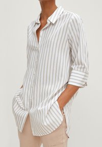 Witte overhem met dunne gouden strepen, opgerolde mouwen en een gebogen zoom. Gemaakt van lichtgewicht stof met een casual pasvorm.