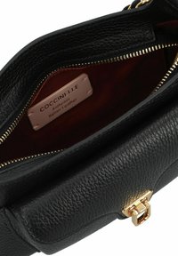 Bolso de cuero negro con superficie texturizada, cremallera dorada y forro de tela marrón. Cuenta con una etiqueta de la marca en el interior.