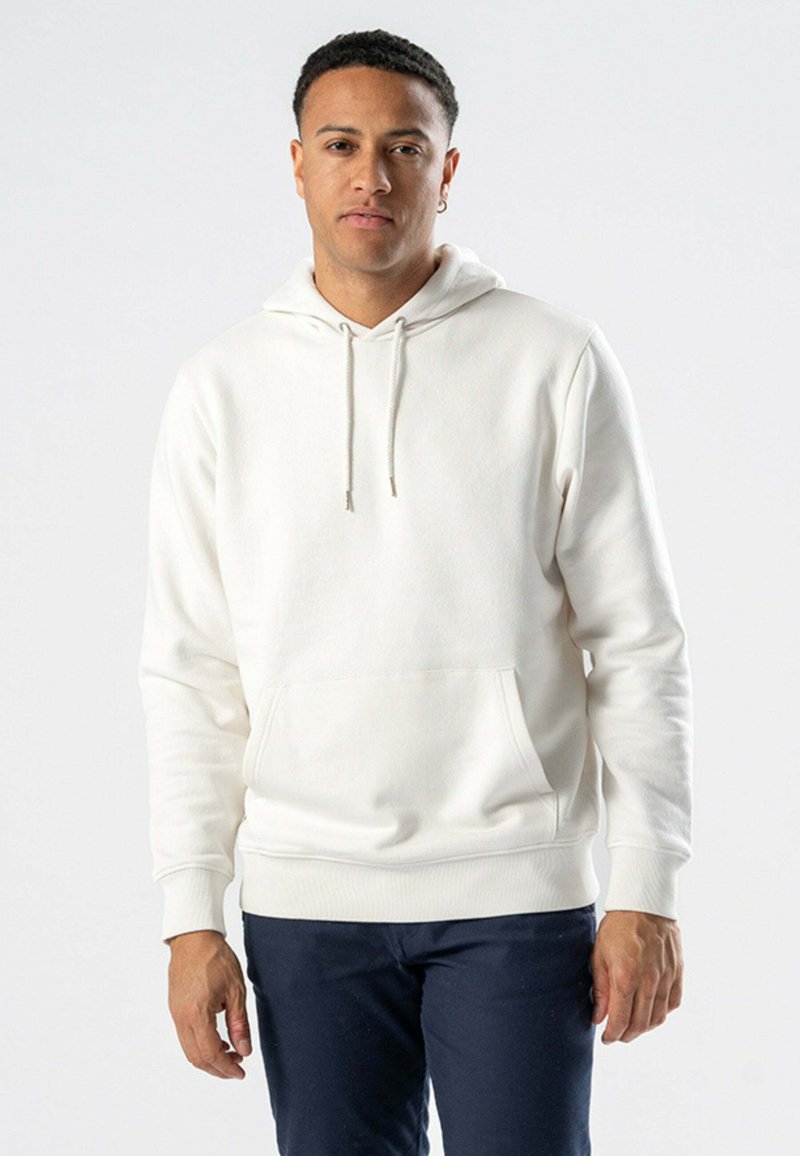 Hvid hættetrøje med en frontlomme, snoretræk i hætten, ribbede manchetter og kant. Modellen bærer navy bukser, med en ensfarvet baggrund.