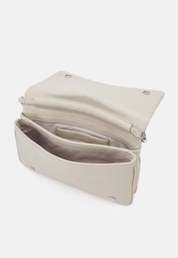Borsa a tracolla sintetica beige con chiusura a pattina, dotata di accessori in metallo argento e numerosi scomparti interni per un'organizzazione ottimale. Texture liscia.