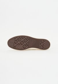 Suela de zapato de goma marrón con un patrón de dibujo geométrico, presentando una punta redondeada y un borde de color claro. Textura suave en general.