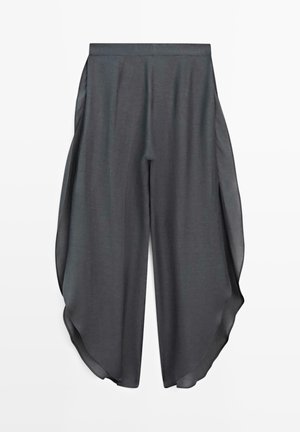 Dunkelgraue, weit geschnittene Hose mit hoher Taille und transparenten Seitenteilen, die an beiden Beinen einen fließenden, drapierten Effekt erzeugen.