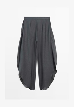 Dunkelgraue, weit geschnittene Hose mit hoher Taille und transparenten Seitenteilen, die an beiden Beinen einen fließenden, drapierten Effekt erzeugen.