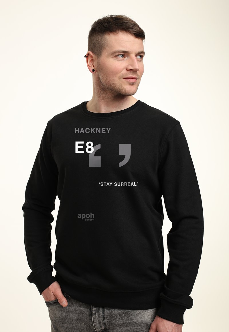 Felpa nera con collo tondo, caratterizzata da testo grigio: "HACKNEY E8" e "'STAY SURREAL'" sulla parte anteriore, realizzata in tessuto morbido.