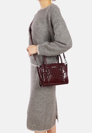 Borsa bordeaux con effetto coccodrillo, dotata di manici doppi e tracolla rimovibile. Texture liscia e lucida, forma rettangolare, dettagli in metallo argentato.