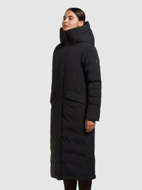 Abrigo negro largo acolchado con cuello alto y estructurado. Presenta dos bolsillos delanteros y una textura lisa y acolchada.