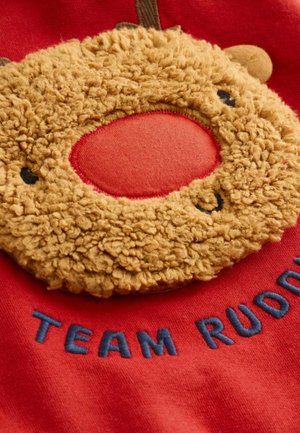 Röd sweatshirt med ett mjukt, beige renhuvud med en cirkulär, röd näsa. "TEAM RUDOLPH" är broderat i blått nedanför.