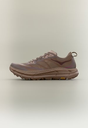 Brązowy niski but sportowy z zapięciem na sznurówki, grubą teksturowaną podeszwą i pętelką z tyłu, prezentowany na neutralnym tle.