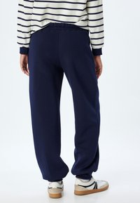 Marineblå sweatpants med elastisk talje og ankelmanchetter, lavet af blødt stof; designet med en afslappet pasform.