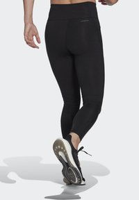 Schwarze Sportleggins mit hohem Bund, schlankem Design und einer Tasche auf der Rückseite. Die glatte Textur und die enge Passform betonen die Bewegung.