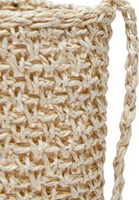 Woven storage basket made of natural fibers. Light tan color with a textured surface. Features a braided handle for easy carrying.