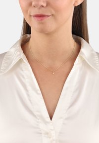 Collarín blando de satén blanco con una cadena dorada y un pequeño colgante de estrella. Diseño sencillo y textura delicada.