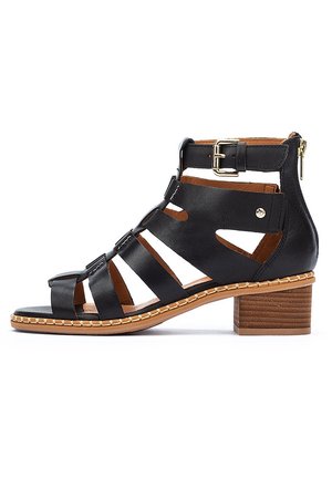 Sort læder gladiatorsandal med blokhæl, ankelrem med spænde, lynlås bagpå og kontrastsyet tan sål.