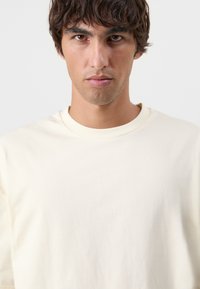 Crèmekleurig katoenen t-shirt met een ronde halslijn en korte mouwen, met een zachte textuur en een relaxed fit.