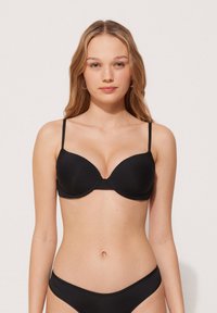 Černá vycpaná podprsenka s nastavitelnými ramínky, hladkým povrchem, podporou drátků a klasickým designem, kombinovaná s odpovídajícími černými bikinami.