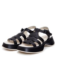 Černé sandály s tkanými horními popruhy, bezpečnou sponou, silnou platformou a kontrastní krémovou stélkou. Texturovaný povrch na popruzích.