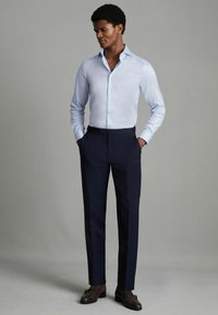 Chemise habillée bleu clair à manches longues associée à un pantalon noir marine et des mocassins marron. Coupe ajustée avec un tissu lisse et élégant.