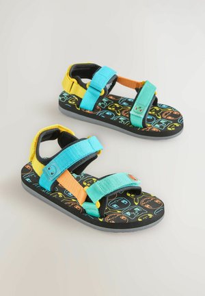 Spalvingi šlepetės su juodu pagrindu, turinčios žaismingą raštą. Pagamintos iš audinio dirželių mėlynos, oranžinės ir geltonos spalvų, su guma padu.