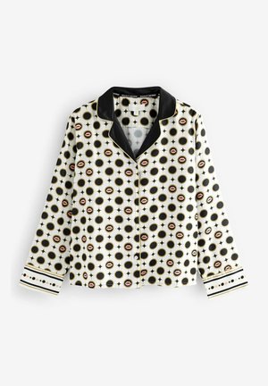 Weißes Langarmhemd mit schwarzem Kragen, verziert mit einem Muster aus schwarzen Kreisen und rosa Lippen, ergänzt durch schwarze und goldene geometrische Designs.
