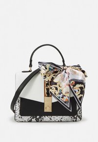 Melns un balts rokas somiņa ar teksturētu čūskādas pamatni, zelta akcentiem un rotājošu šalli ar košiem rakstiem, kas saiņota ap rokturi.