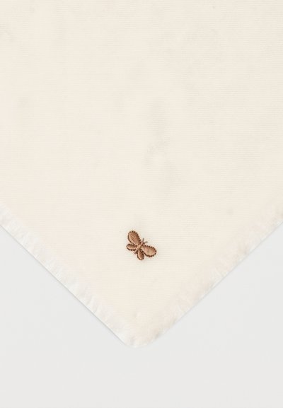 Τετράγωνο ύφασμα εκρού με μικρή καφέ κεντητή πεταλούδα κοντά σε μια γωνία σε ανοιχτό φόντο.