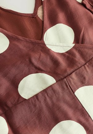 Bordeaux-kangasmekko, jossa on suuria vaaleanharmaita pilkkuja. V-pääntie, jossa on teksturoitu pinta ja päällekkäisiä kangasosioita.