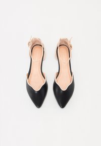 Scarpe nere in pelle con punta appuntita e accenti nude, design slingback e texture liscia. Presentano un cinturino alla caviglia sicuro.