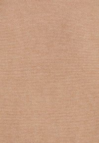 Beżowa dzianina o drobnej teksturze, jednolitym wzorze i miękkim wyglądzie, odpowiednia do odzieży lub tapicerki.