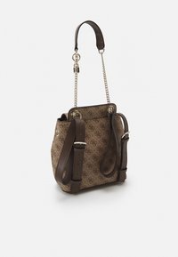 Sac à dos marron à motifs avec des bretelles en cuir ajustables et une courte poignée chaîne dorée sur fond blanc.