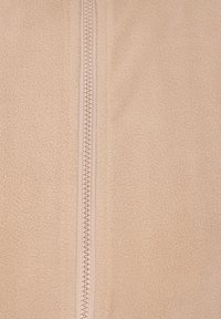 Tessuto felpato beige con una texture liscia e una zip centrale. Le cuciture sono di un colore chiaro abbinato, garantendo un design coerente.
