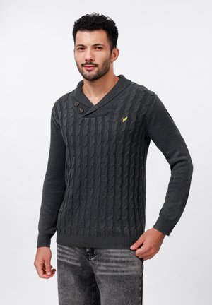 Suéter de punto gris oscuro con un patrón de trenzas, cuello chal y dos botones. Presenta un pequeño logo amarillo en el pecho.