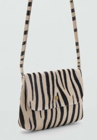 Borsa a tracolla con motivo zebra e texture in morbida pelliccia. Presenta una chiusura a pattina e una sottile tracolla a righe.Schema dei colori: beige e nero.