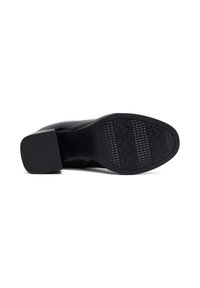 Calzado negro con un upper brillante, punta redondeada y una suela de goma texturizada que presenta un patrón geométrico para mayor agarre.