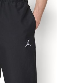Schwarze Sportshorts aus leichtem Material, mit einem elastischen Bund und einem weißen Jumpman-Logo auf dem linken Oberschenkel.