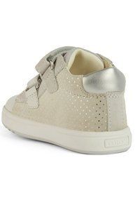 Zapato de ante gris claro con diseño perforado, dos cierres de tiras y un acento de tacón metálico plateado. Suela de goma blanca con agarre texturizado.