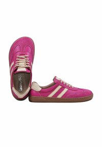 Paire de baskets en cuir rose avec des rayures beige, des lacets et des accents au niveau du talon, doté de semelles en caoutchouc marron sur un fond blanc.