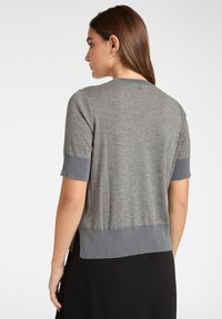 Maglione grigio a maniche corte in maglia con scollatura rotonda, polsini a contrasto e un piccolo logo sul retro. Tessuto morbido e design aderente.