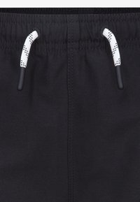Shorts noirs avec une taille élastique, dotés d'un cordon blanc avec des accents noirs et de coutures décoratives sur le côté.