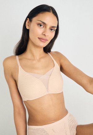 Beige myk stoff-BH med V-formet design, mesh-detalj, justerbare stropper og subtil tekstur med ribber. Glatt overflate, ingen synlige festemidler.