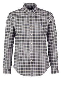 Camisa de cuadros en tonos marino, verde y crema. Presenta un cuello, mangas largas y un dobladillo curvado. Fabricada con tejido entrelazado.