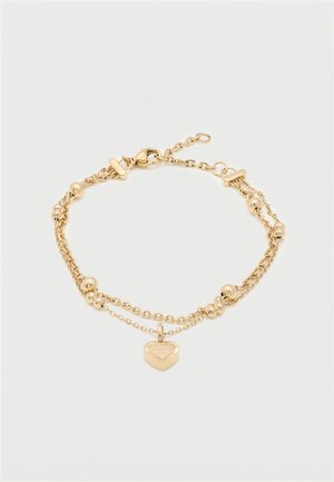 Bracelet chaîne à double couche en or avec de petites billes en or et un pendentif en forme de cœur sur un fond blanc.