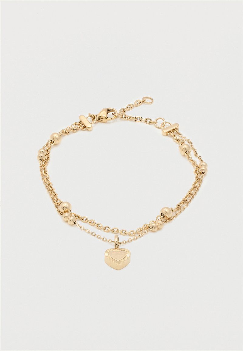 Διπλό χρυσό βραχιόλι με μικρές χρυσές χάντρες και μενταγιόν σε σχήμα καρδιάς σε λευκό φόντο.