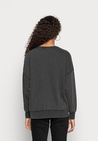 Dark gray oversized sweatshirt with a round neck, wide sleeves, and ribbed cuffs. Soft texture and slightly longer back hem.