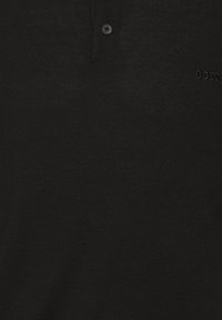 Polo en maille noire avec deux boutons et le logo "BOSS" subtilement brodé sur la poitrine.