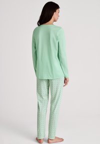 Mintgroene lange mouw top en bedrukte pyjamabroek, met een geometrisch ontwerp in een lichtere tint, gemaakt van zachte, ademende stof.